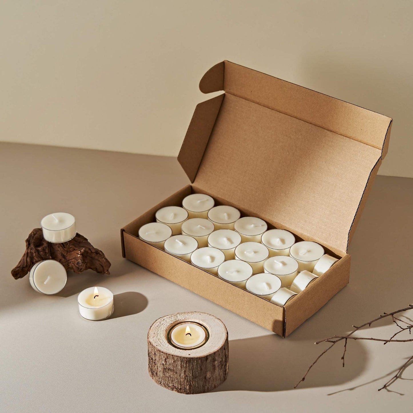 갈색 종이 상자 속에 가득 담긴 티라이트 캔들과 옆에 놓인 우드 장식이 함께 보이는 캔들 연출 사진