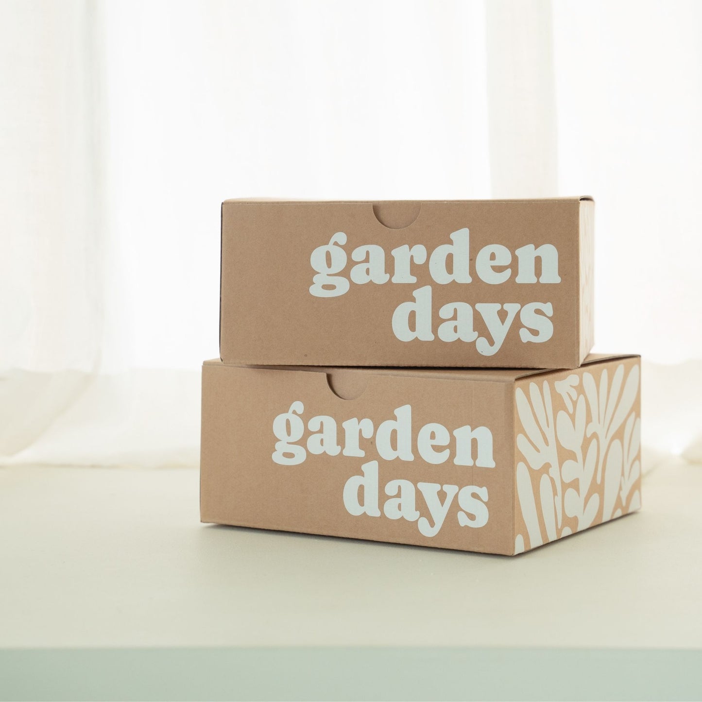 garden days 로고가 인쇄된 크라프트 상자 두 개를 포개어 쌓아놓은 티라이트 캔들 패키지 연출 사진