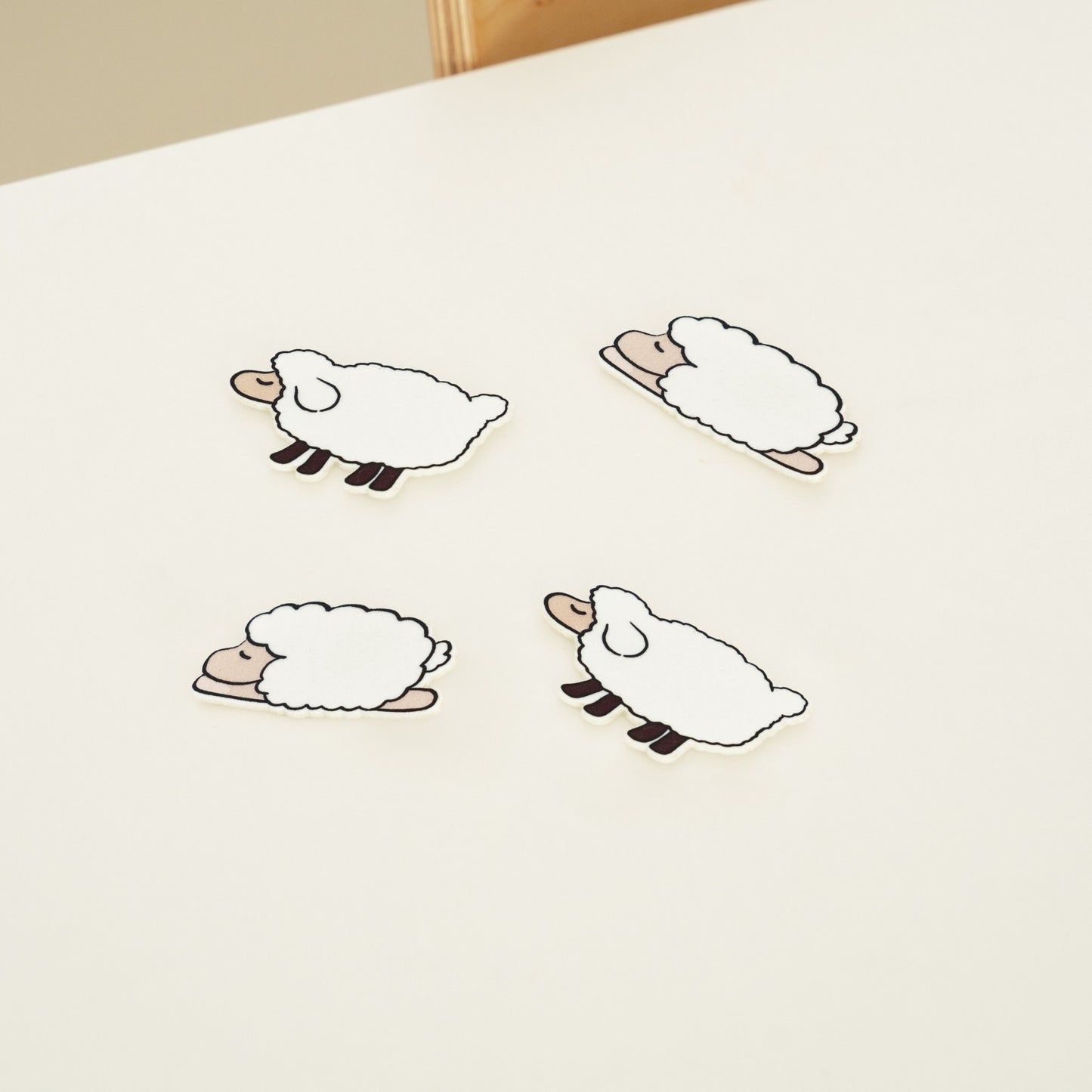 밝은 침대 위에 서로 다른 포즈의 양 모양 슬리피펠트 세 장이 놓여 있는 제품 사진