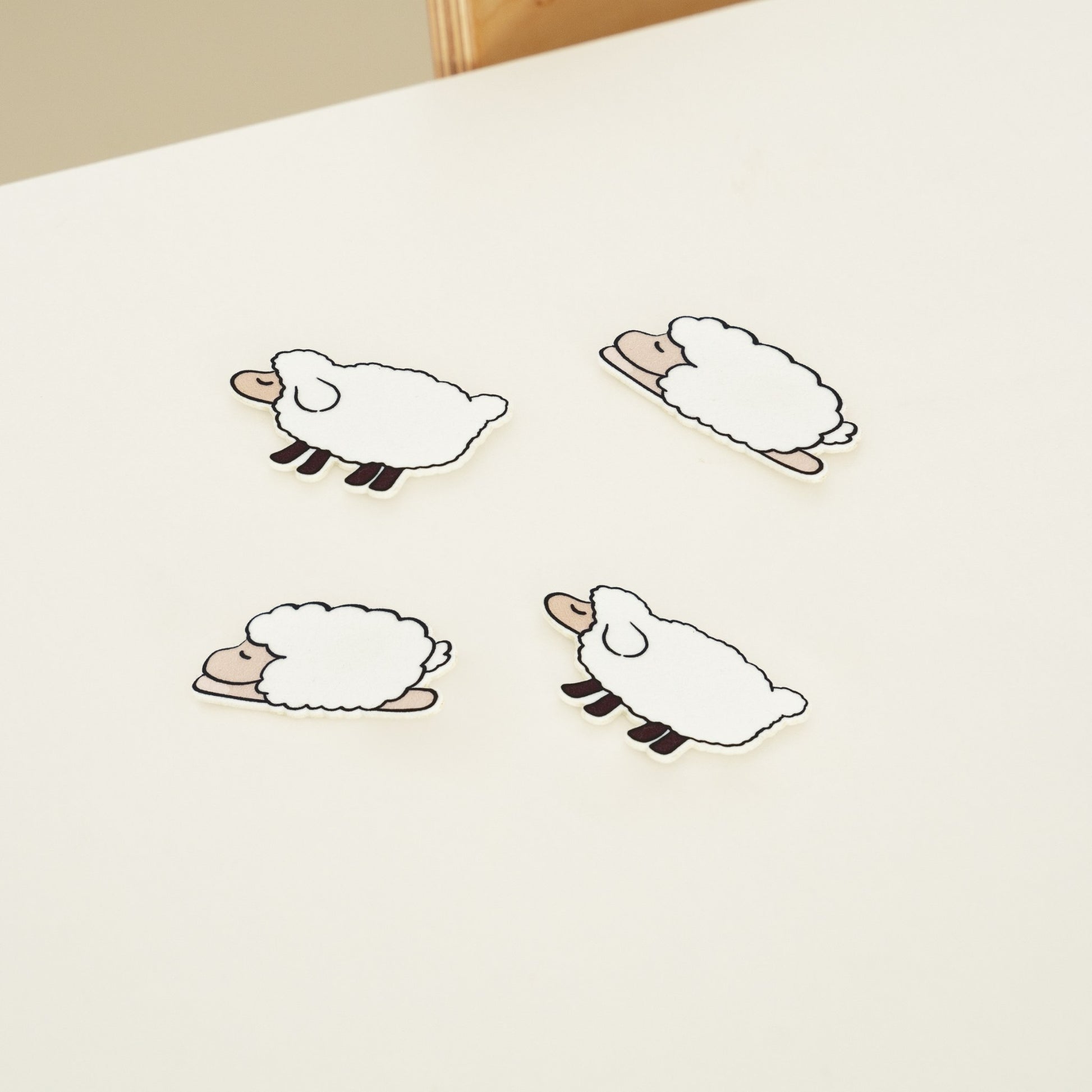 밝은 침대 위에 서로 다른 포즈의 양 모양 슬리피펠트 세 장이 놓여 있는 제품 사진