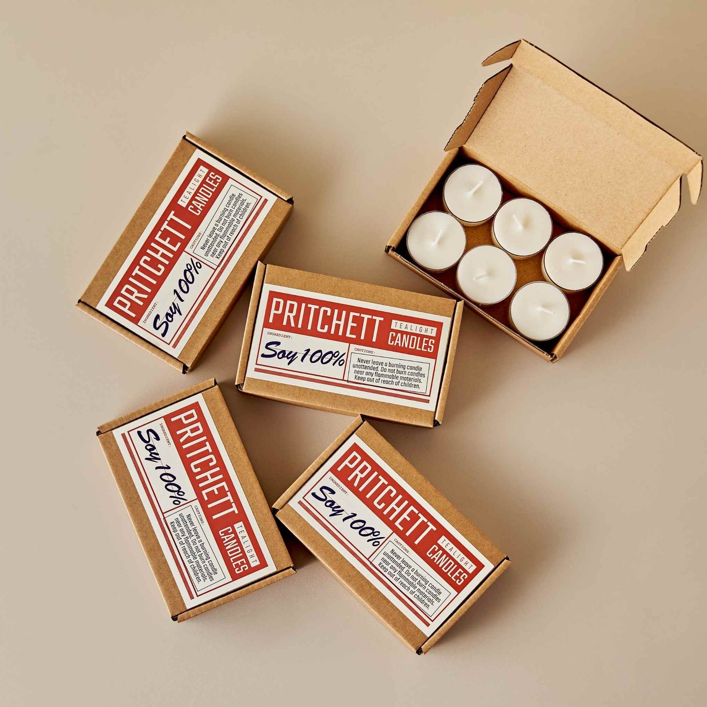 상단에서 내려다본 구성으로, 갈색 종이 박스에 담긴 티라이트 캔들과 주변에 놓인 여러 개의 캔들 박스가 있는 사진 