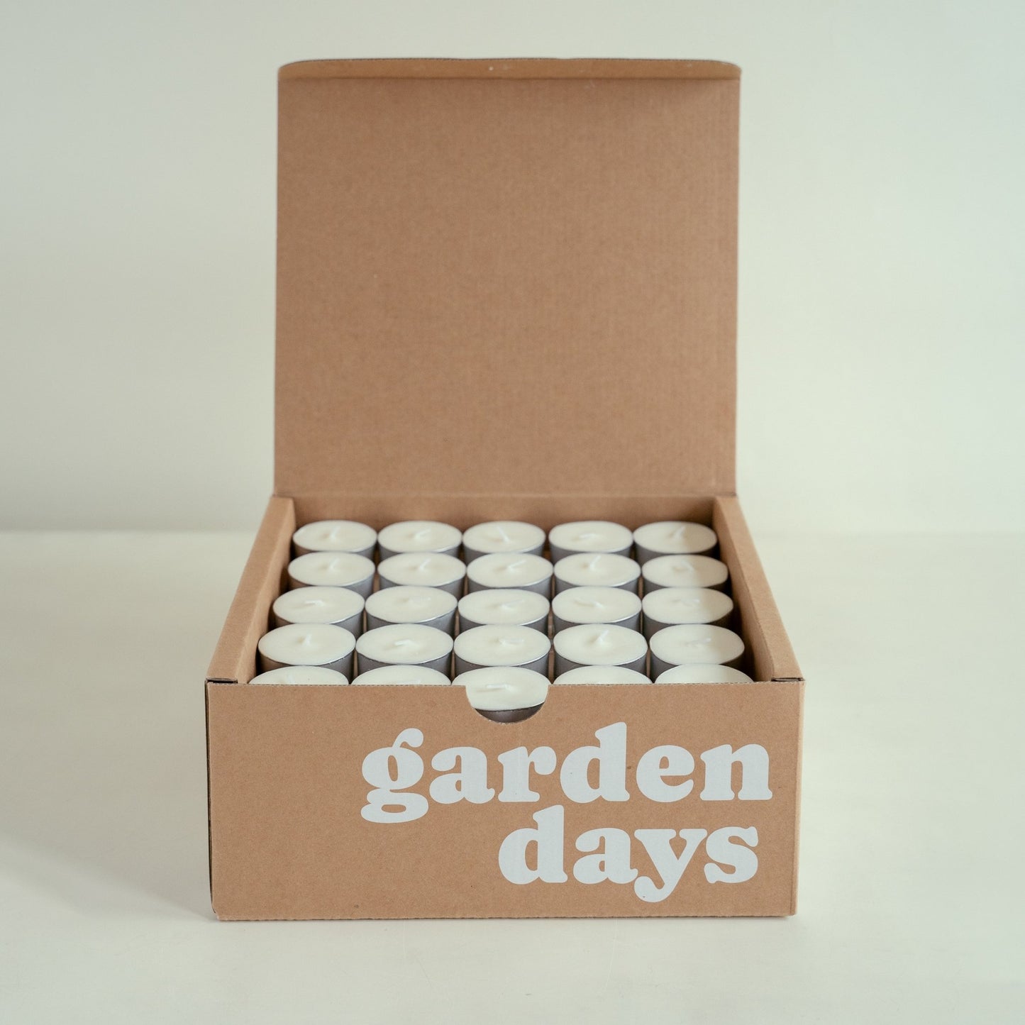garden days 로고가 인쇄된 크라프트 박스 안에 흰색 티라이트 캔들이 가득 담긴 제품 사진