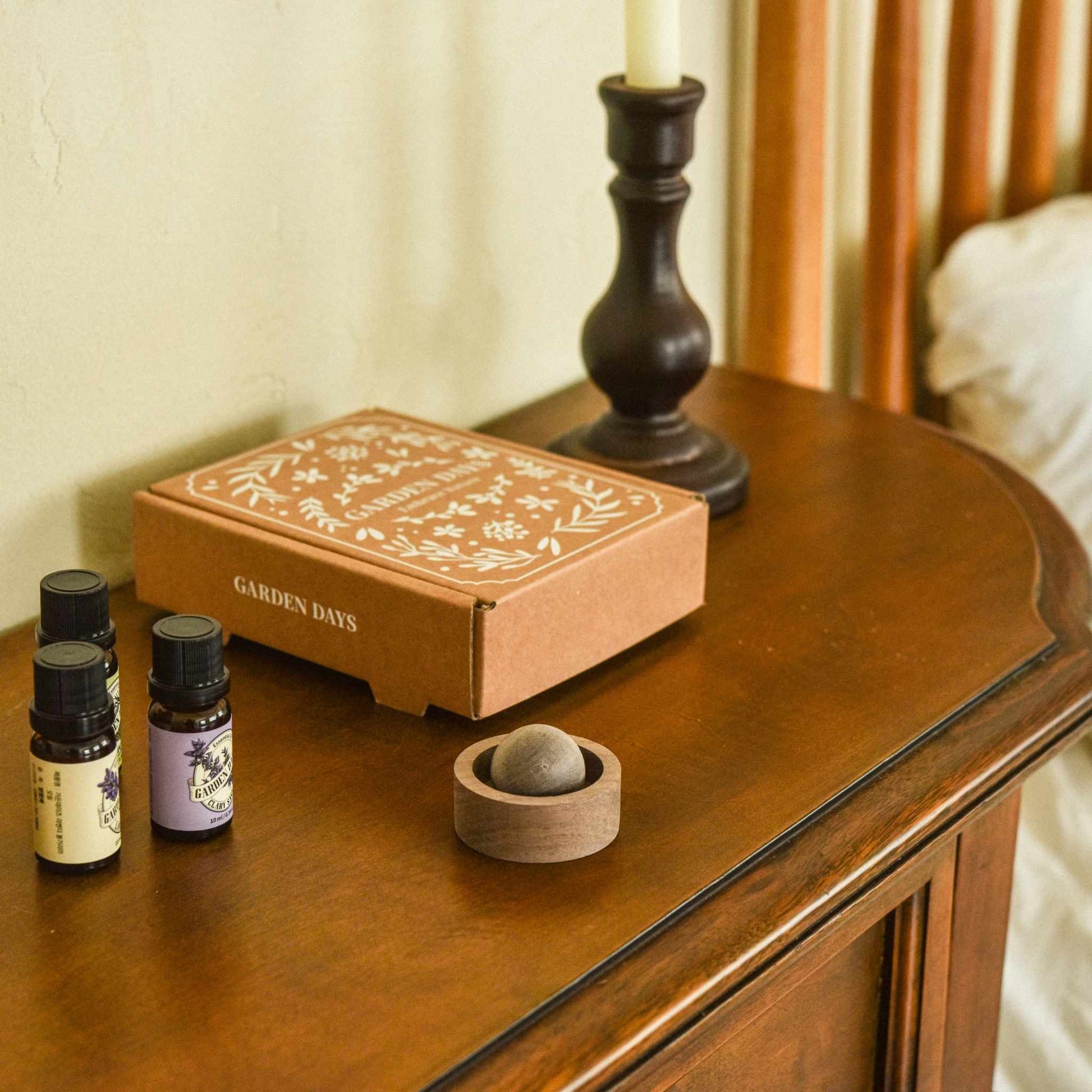 콘솔 테이블 위 촛대와 함께 놓인 호두 브리즈볼 선물세트 상자와, 앞에 꺼내 둔 호두 브리즈볼과 에센셜오일들이 병들이 보이는 선물 연출 사진