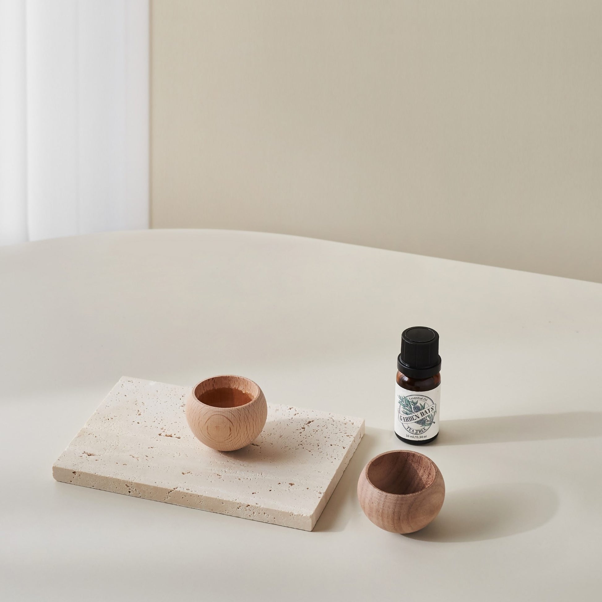 테라조 느낌의 트레이 위에 올려진 밝은 색 에그 브리즈볼과 진한 색 에그 브리즈볼, 옆에 세워둔 가든데이즈 에센셜오일 병이 보이는 제품 연출 사진