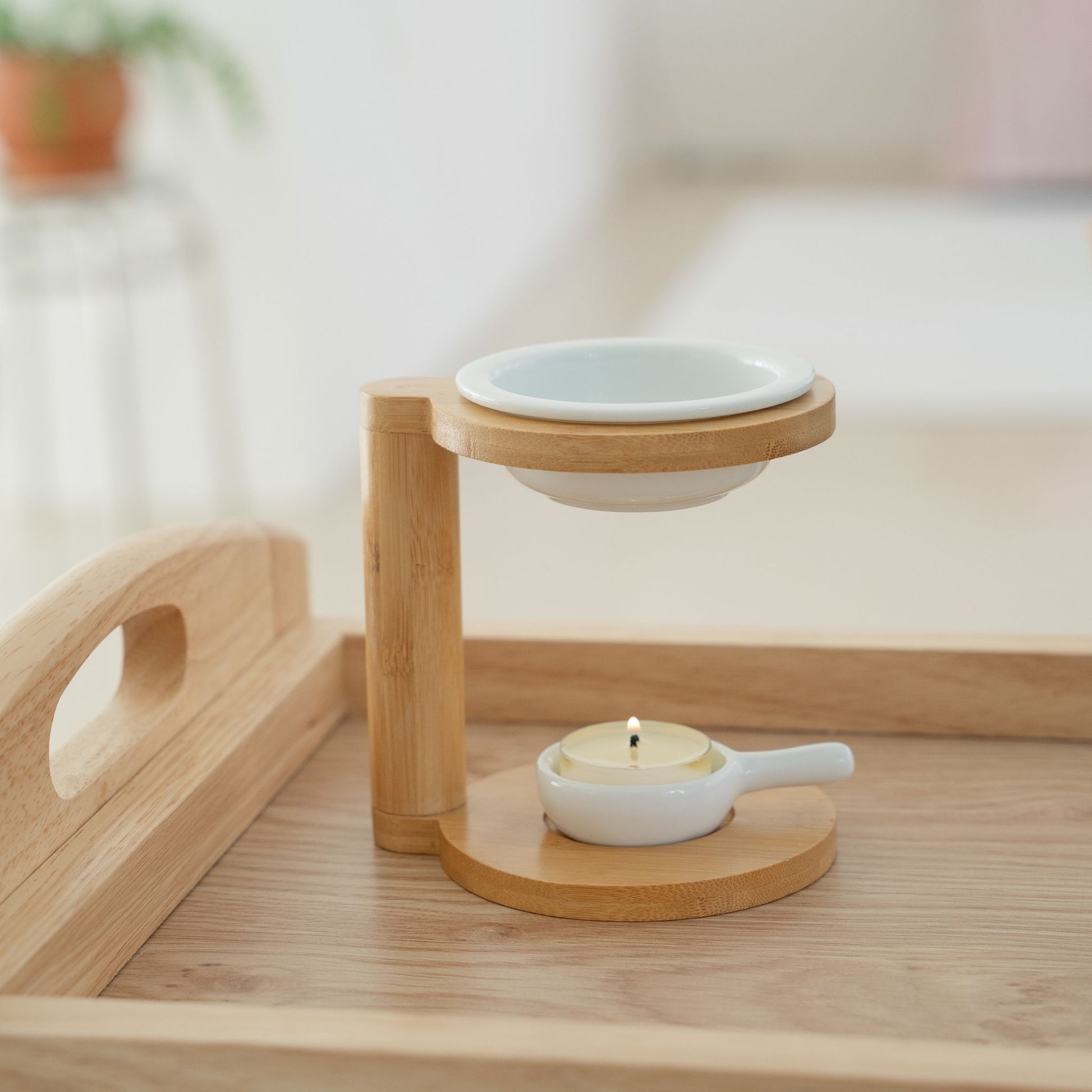 밝은 방 안 나무 트레이 위에 놓인 우드 오일버너와 상단 세라믹 접시, 아래 은은하게 켜진 티라이트 캔들이 보이는 연출 사진