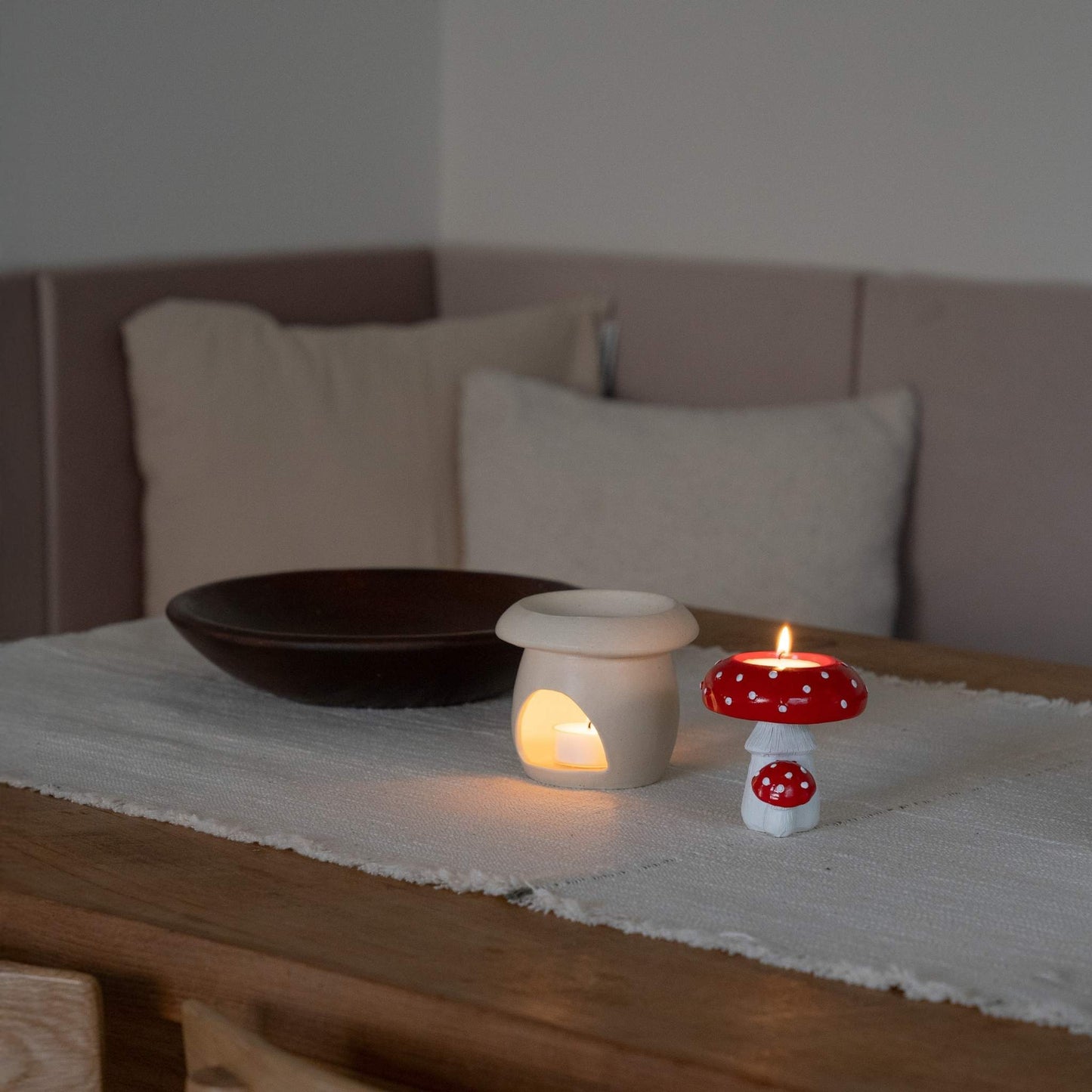 식탁 위 러너 천 위에 놓인 베이지 색 머쉬룸 오일버너와 붉은 버섯 모양 티라이트 캔들이 함께 연출된 사진
