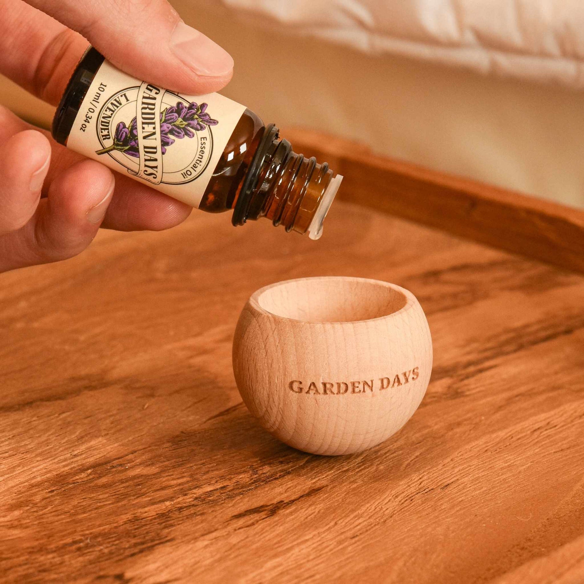 우드 바닥 위 에그 브리즈볼 우드 발향 제품 안으로 가든데이즈 천연 100% 에센셜오일을 떨어뜨리는 손이 보이는 사용 방법 연출 사진